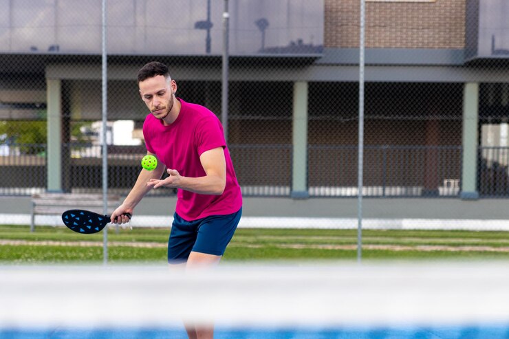 Retrato de un hombre realizando un servicio en pickleball El deportista jugador de tenis de pickleball entrena en la cancha al aire libre usando una raqueta para golpear la pelota