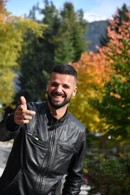 Foto retrato de un hombre riendo de pie contra los árboles