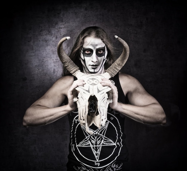 Foto retrato de hombre con ropa de estilo gótico con calavera en la mano