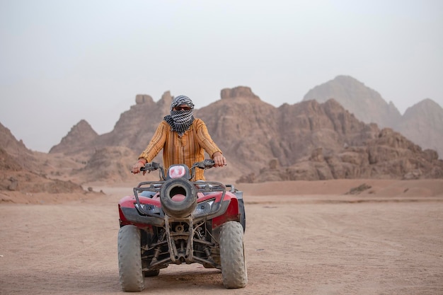 Retrato de un hombre en un safari de quads ATV en el desierto cerca de Sharm El Sheikh Egipto Motocicletas ATV de tracción a las cuatro ruedas todoterreno rápidas y potentes en el rally del desierto arenoso contra las altas montañas