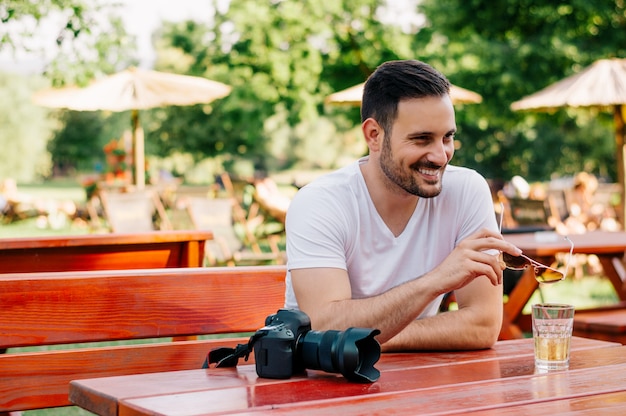 Retrato de hombre sentado en la cafetería, con gafas de sol