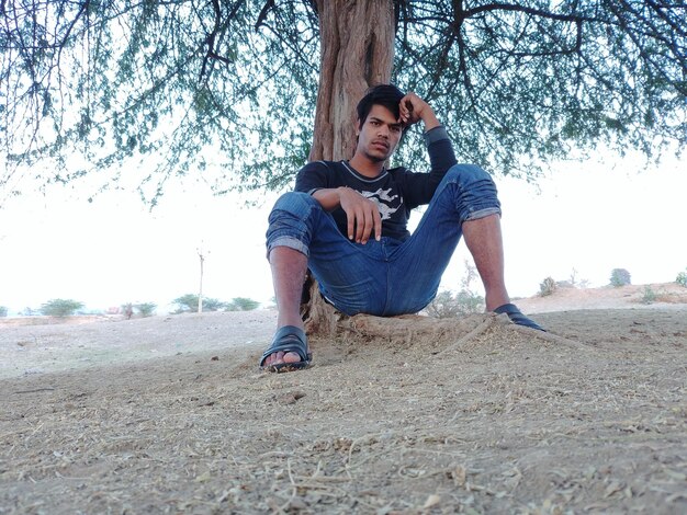 Foto retrato de un hombre sentado contra un árbol