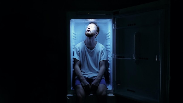 Foto retrato de un hombre sentado en un refrigerador