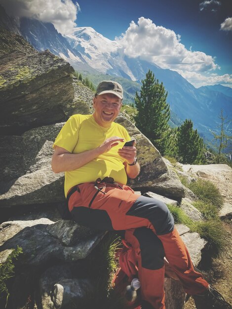 Foto retrato de un hombre sentado en una roca contra una montaña