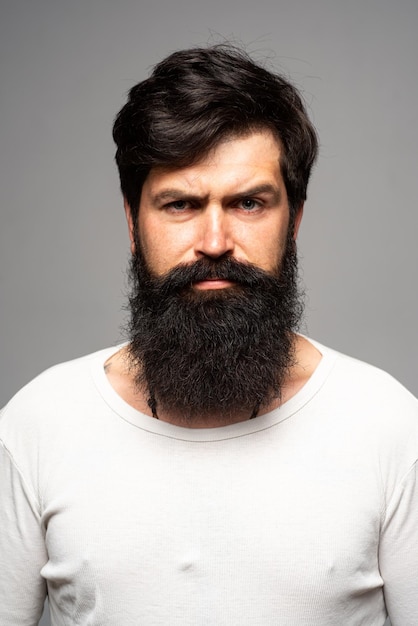 Retrato de hombre serio confiado tiene barba y bigote, parece serio, aislado. Pensando en chico barbudo con estilo.
