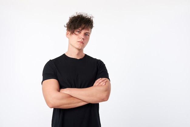 Retrato del hombre serio joven atractivo atractivo que lleva una camiseta negra de manga corta del algodón que presenta en estudio.