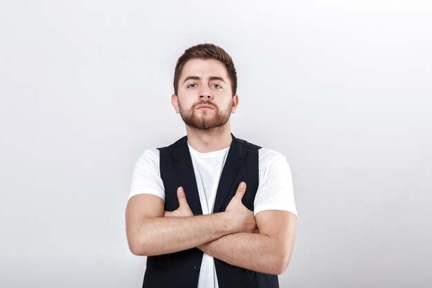 Retrato de hombre serio joven guapo con cabello oscuro en camisa blanca sobre fondo gris