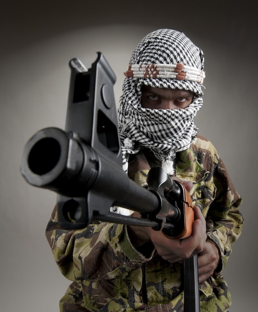 Retrato de hombre serio del Medio Oriente con AK-47 apuntando hacia ti