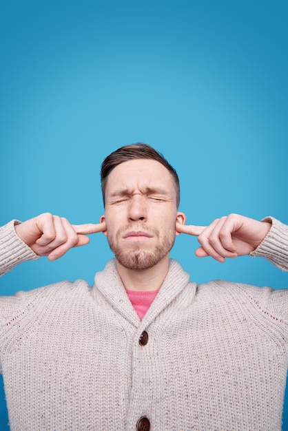 Foto retrato de hombre serio tapándose los oídos