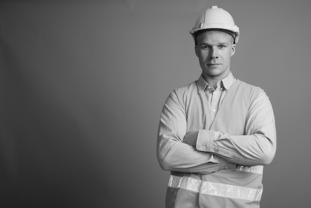 Retrato de un hombre con sombrero de pie contra un fondo gris