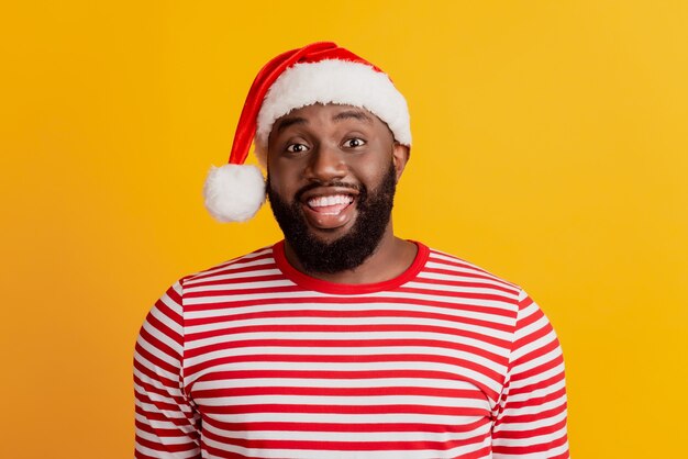 Retrato de hombre con sombrero de santa sonrisa radiante con dientes en la pared amarilla