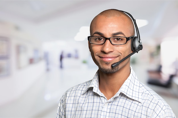 Retrato de un hombre sonriente con auriculares trabajando como operador de centro de llamadas