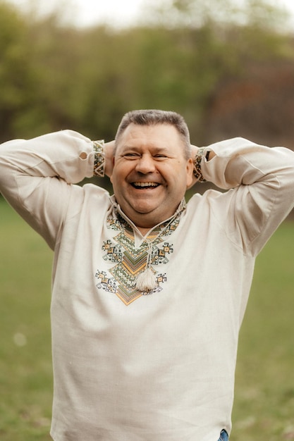 Retrato de un hombre sonriente con una camisa bordada en un fondo del parque