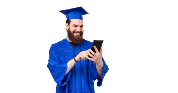 Retrato de hombre sonriente estudiante barbudo en licenciatura con tableta sobre fondo blanco.