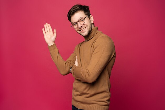 Retrato de hombre sonriente con la mano levantada en señal de saludo. Concepto de alta cinco