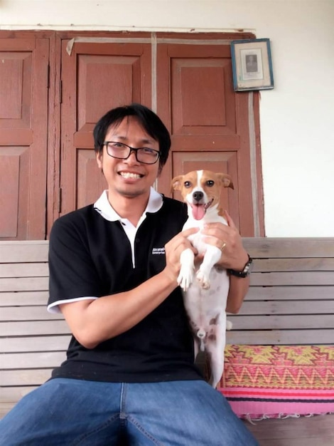 Foto retrato de un hombre sonriente con un perro sentado en un banco