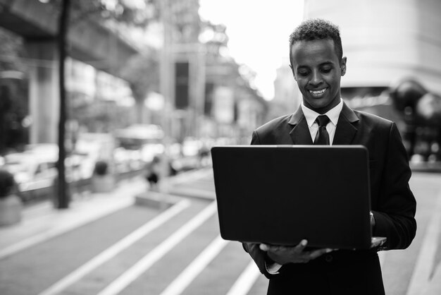 Foto retrato de un hombre sonriente de pie en la ciudad