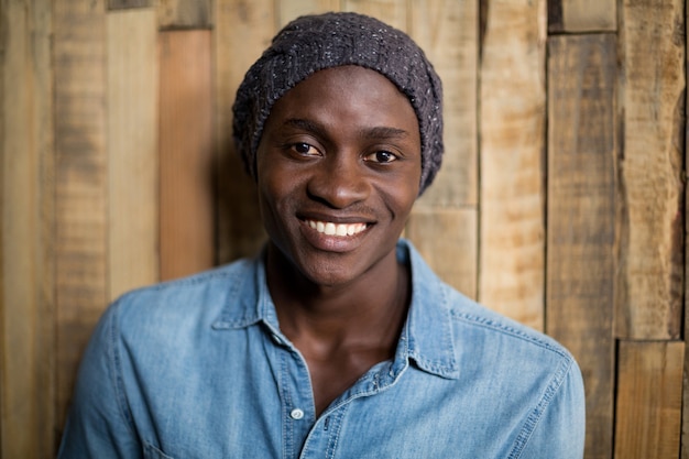 Retrato de hombre sonriente de pie contra la pared de madera