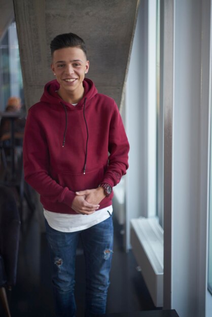 Retrato de un hombre sonriente de pie junto a la ventana mientras está en casa