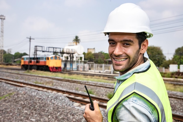 Foto retrato de un hombre sonriente de pie en la vía del ferrocarril