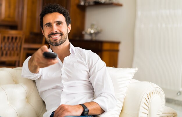 Retrato de un hombre sonriente que elige un programa para mirar en la televisión