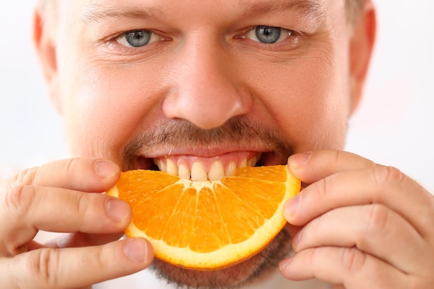 Retrato de hombre sonriente con rodaja de naranja jugosa