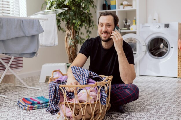 Retrato de un hombre sonriente sentado en el cuarto de lavado del piso del baño haciendo tareas domésticas clasificando