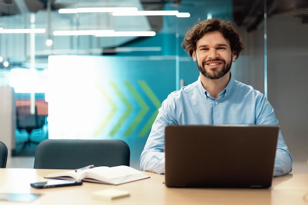 retrato, de, hombre sonriente, usar la computadora portátil, y, posar