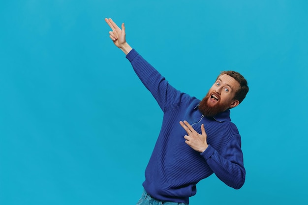 Retrato de un hombre con una sonrisa de suéter y signos y símbolos de mano de felicidad sobre un fondo azul Lugar de copia positiva de estilo de vida