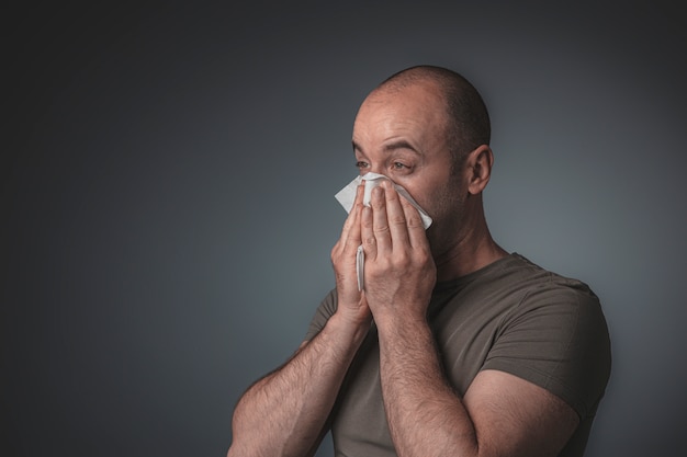 Retrato de un hombre soplando su nariz con un pañuelo