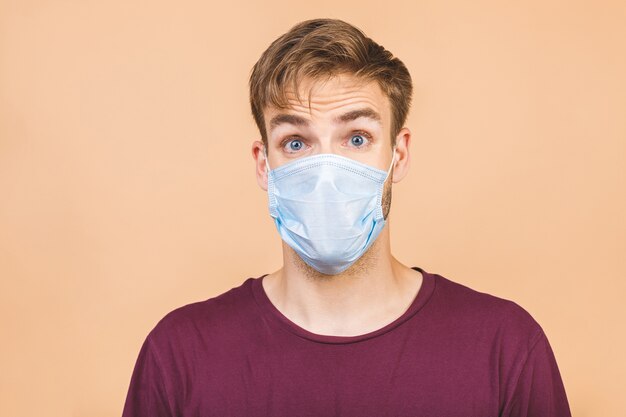 Retrato de hombre sorprendido joven guapo con máscara médica quirúrgica