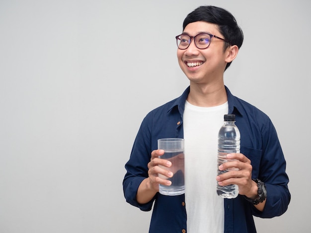 Retrato hombre sostenga una botella de agua con vasos de agua sonrisa suave mirando el espacio de la copia