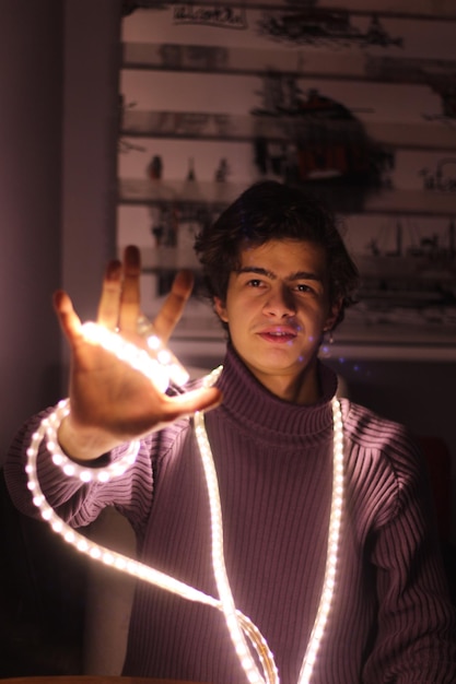 Foto retrato de un hombre sosteniendo una luz de cuerda iluminada mientras está de pie en casa