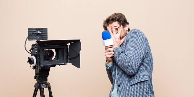 Retrato de un hombre y su cámara sobre un fondo crema