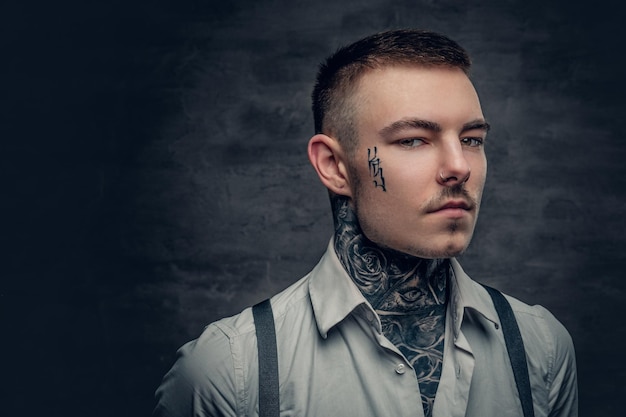 Retrato de un hombre tatuado con camisa blanca y tirantes.