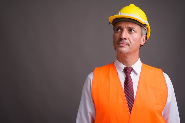 Retrato de hombre trabajador de la construcción contra la pared gris