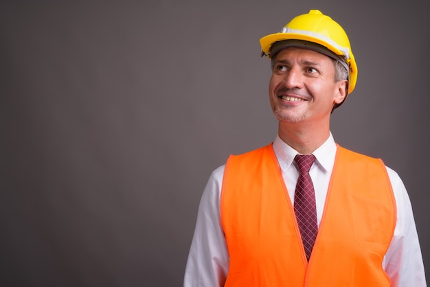 Retrato de hombre trabajador de la construcción contra la pared gris