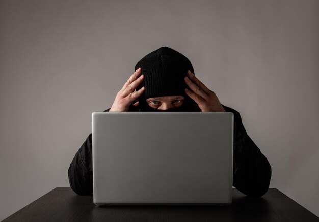 Retrato de un hombre usando una computadora portátil en la mesa contra la pared