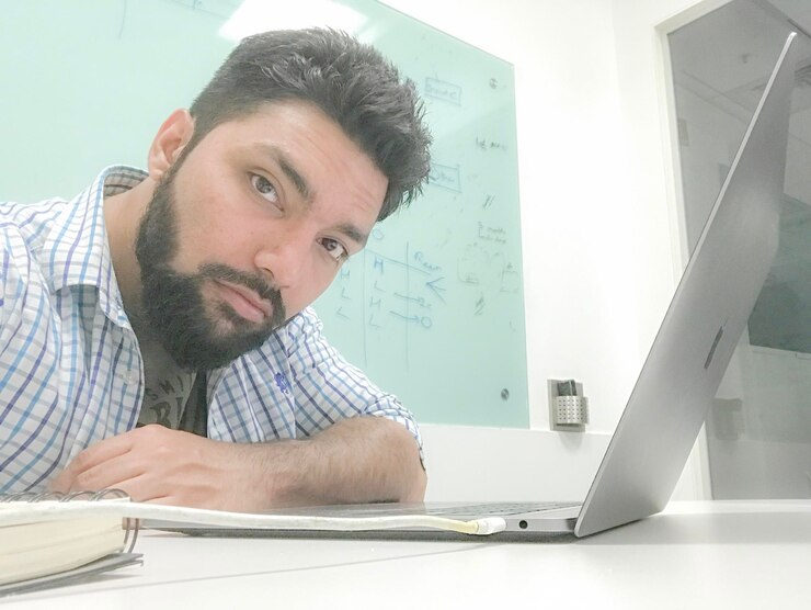Foto retrato de un hombre usando una computadora portátil mientras está sentado en la oficina