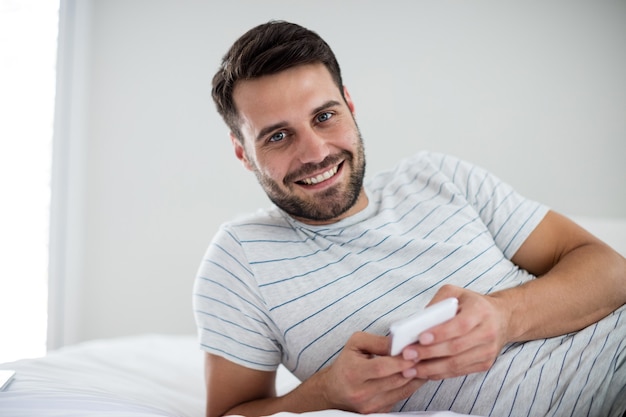 Retrato, de, hombre, utilizar, teléfono móvil, en cama, en, dormitorio