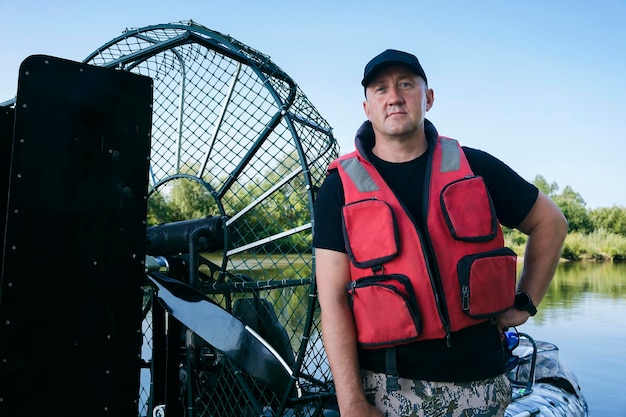 Retrato de un hombre de vacaciones en la naturaleza montando un hidrodeslizador en el río con ropa de cazador