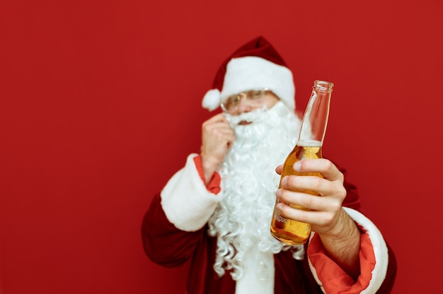 Retrato hombre vestido como Santa Claus sosteniendo una botella de cerveza