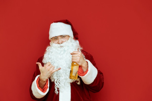 Retrato hombre vestido como Santa Claus sosteniendo una botella de cerveza