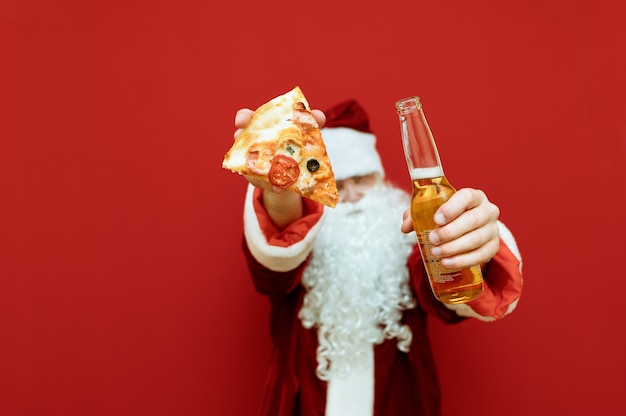 Retrato de hombre vestido como Santa Claus sosteniendo pizza y cerveza