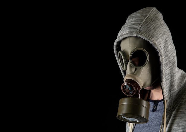 Retrato de un hombre en una vieja máscara militar de gas sobre un fondo negro. Copia espacio