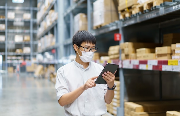 Retrato de hombres asiáticos, personal, conteo de productos Gerente de control de almacén De pie, contando e inspeccionando productos en el almacén