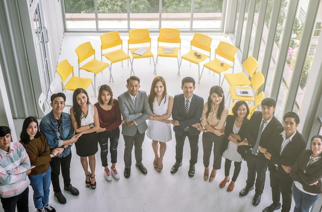 Retrato de hombres de negocios sonrientes tomados de la mano mientras están de pie en la oficina