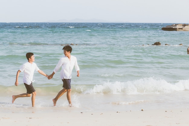 Foto retrato homosexual joven pareja asiática corriendo juntos en la playa.