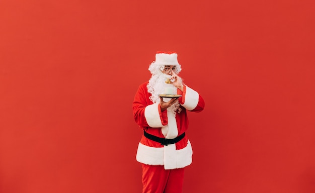 Retrato horizontal de meio corpo de um Papai Noel positivo tocando seus óculos