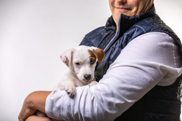 Retrato horizontal de um homem bonito e alegre segurando Jack Russell Terrirer, com expressão alegre